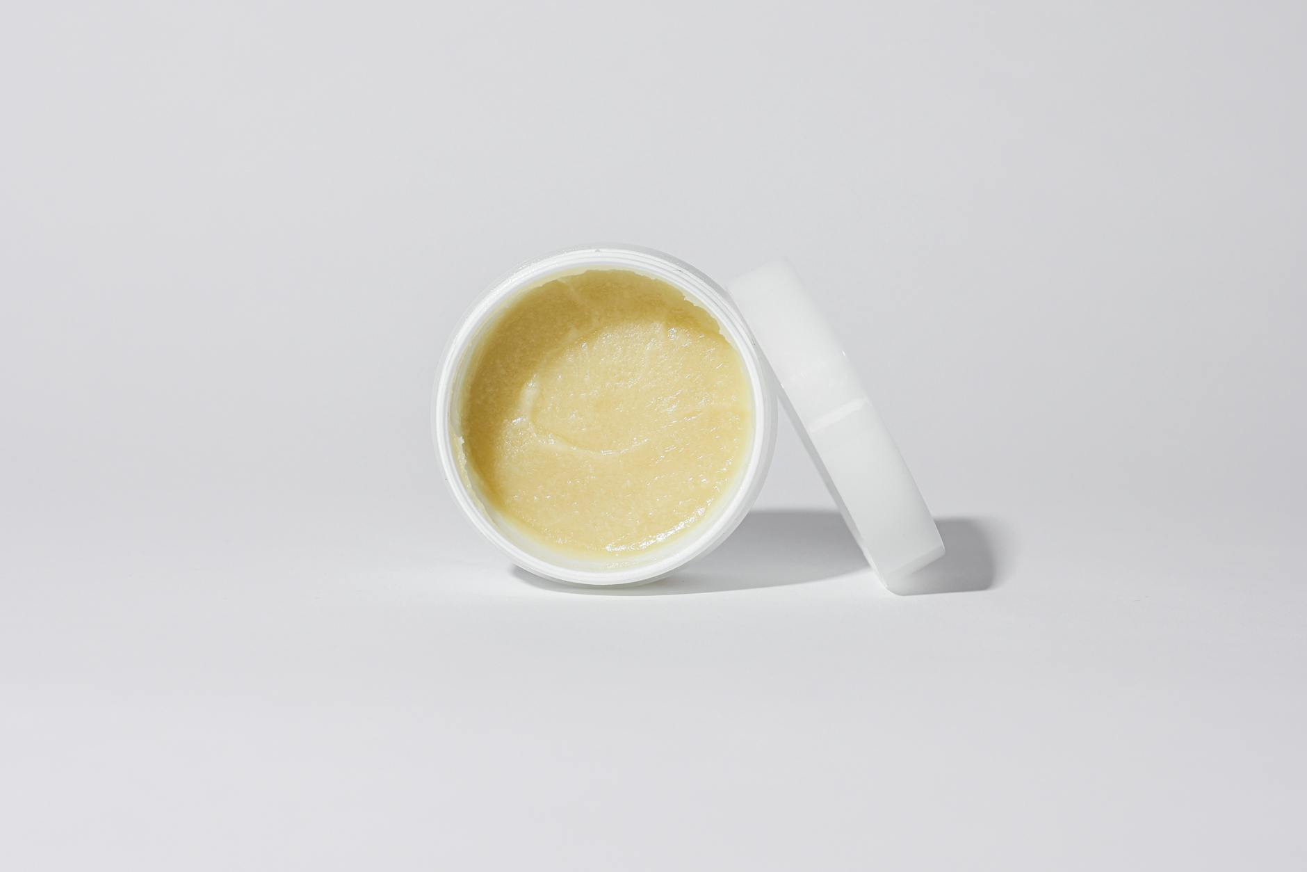 Biały słoiczek z kremem kosmetycznym na neutralnym tle