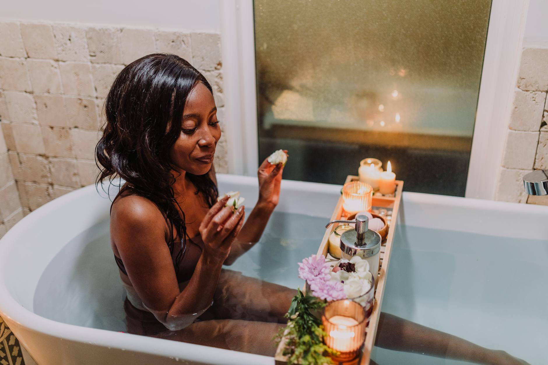Kobieta w relaksującej kąpieli z aromaterapią, świecami i kwiatami