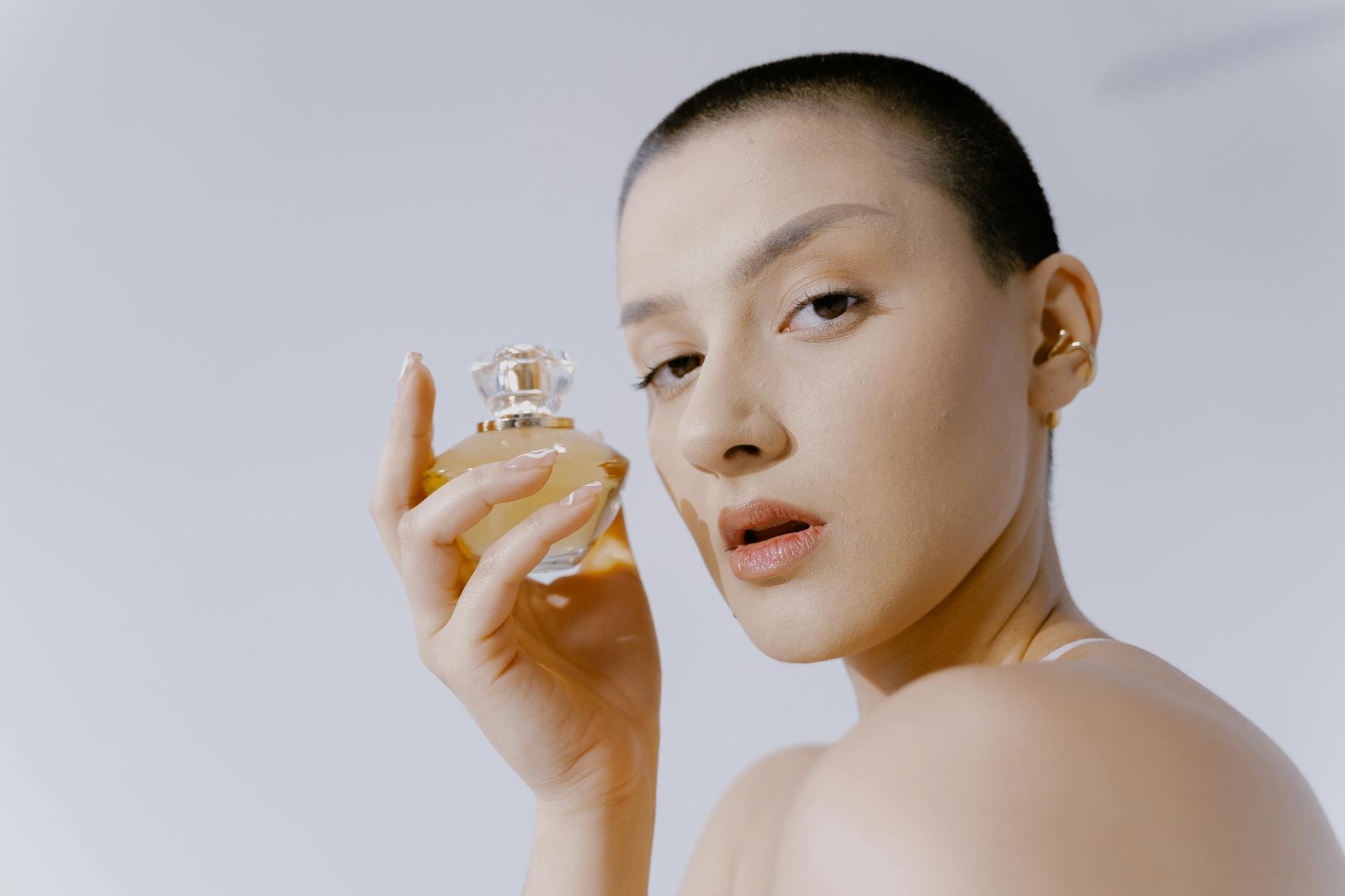 Elegancka kobieta z krótkimi włosami trzymająca flakon perfum
