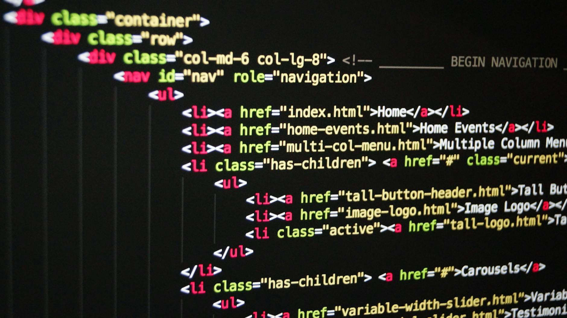 Kolorowy kod HTML na ekranie monitora symbolizujący pracę programisty