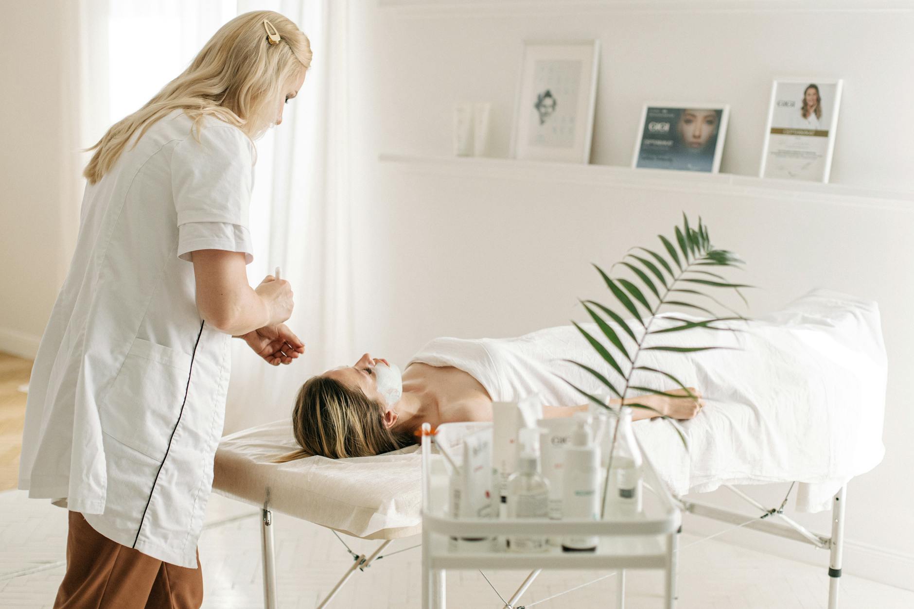 Kosmetyczka wykonuje relaksujący zabieg na twarzy klientki w SPA