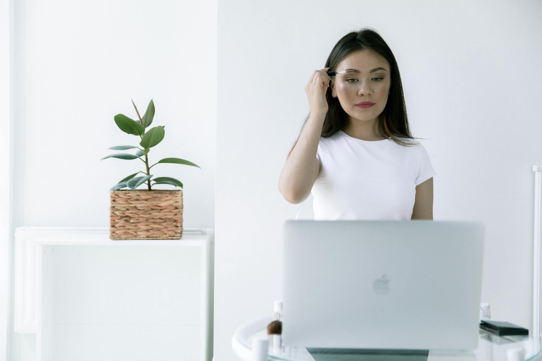 Kobieta w domu nakłada makijaż, używając laptopa zamiast lustra