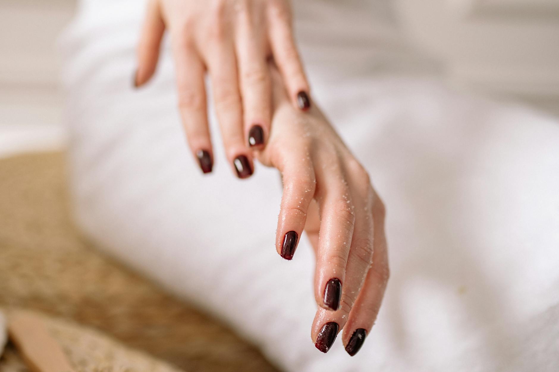 Zadbana kobieca dłoń z ciemnym lakierem na tle spa
