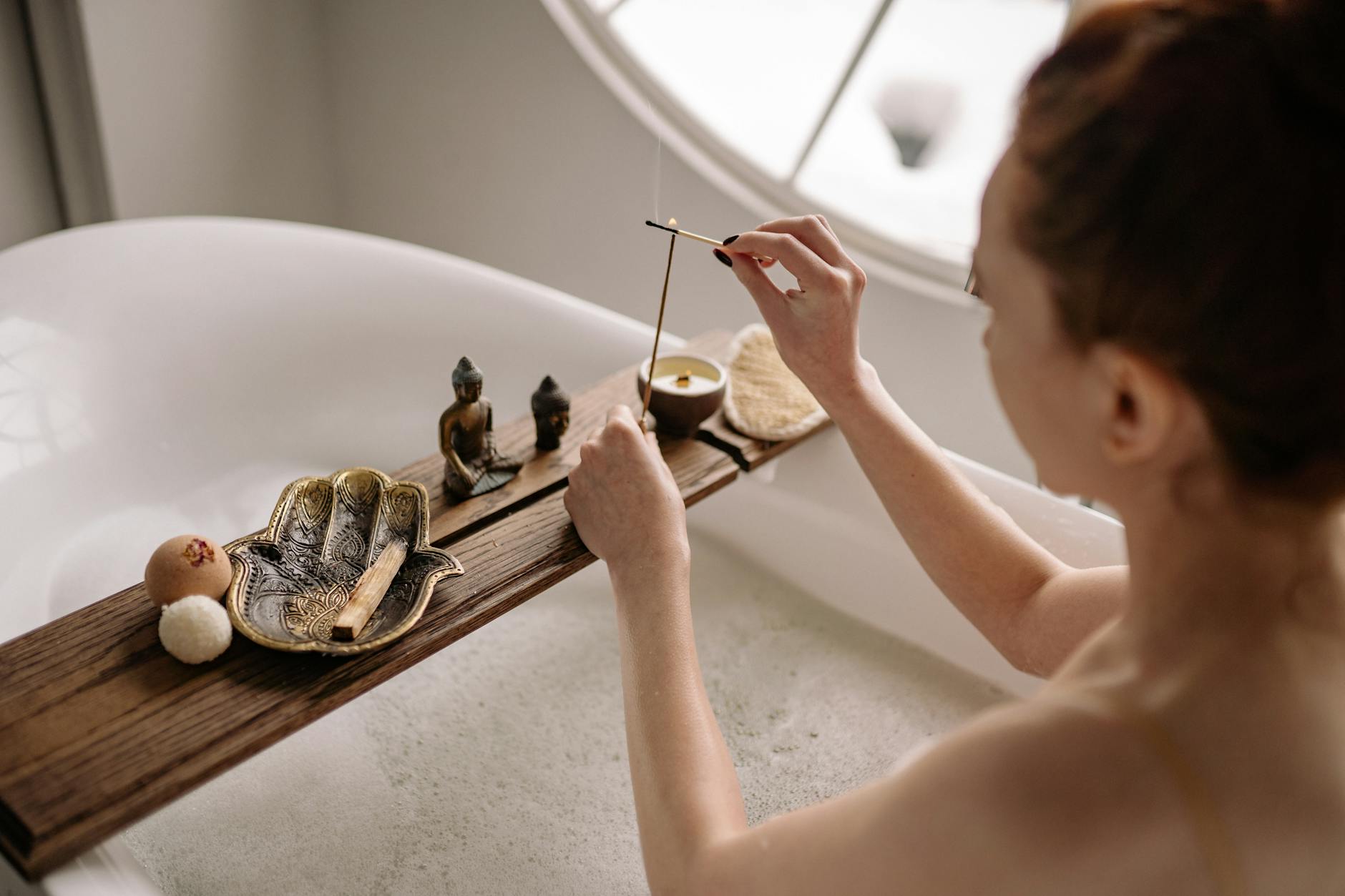 Kobieta w relaksującej kąpieli z kadzidłem i tacą spa na wannie