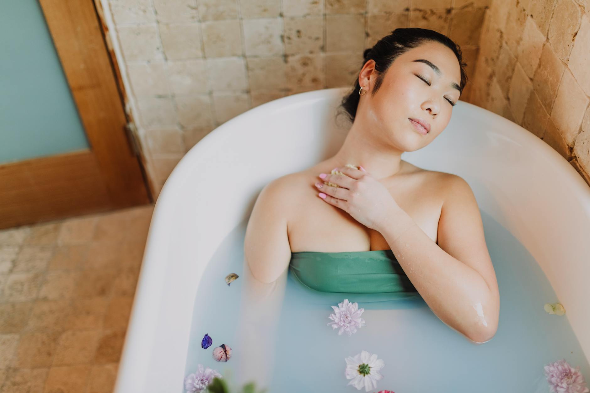 Azjatka relaksuje się w wannie z kwiatami podczas domowego rytuału spa