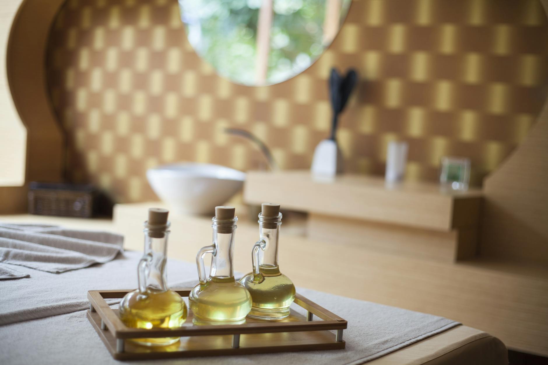 Butelki naturalnych olejków na drewnianej tacy w eleganckim pokoju spa